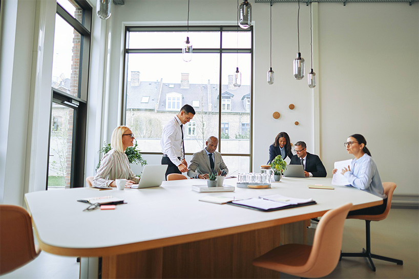 Group of business people sitting at a large table in front of a window