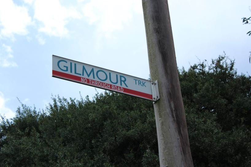 A signpost with a street sign attached, which says Gilmour Track