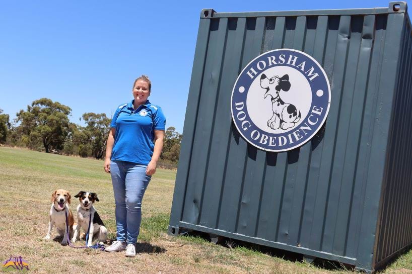 Picture of a woman with two dogs in front of a sign that says Horsham Dog Obedience