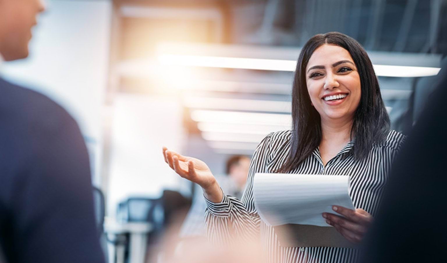 A business woman holding a notepad and talking to colleagues